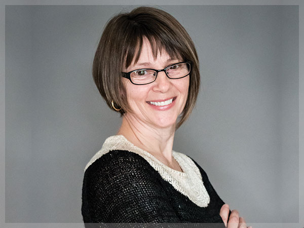 Portrait of Deborah Murchie, Sales Representative, in a dark jacket against a grey studio background